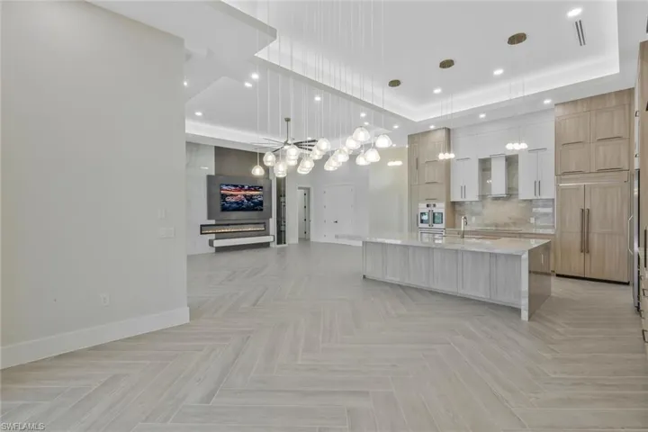 Kitchen featuring open floor plan, light stone counters, hanging light fixtures, modern cabinets, and tasteful backsplash