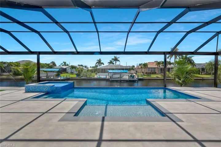 View of pool with a water view, a lanai, a pool with connected hot tub, a sunroom, and a residential view