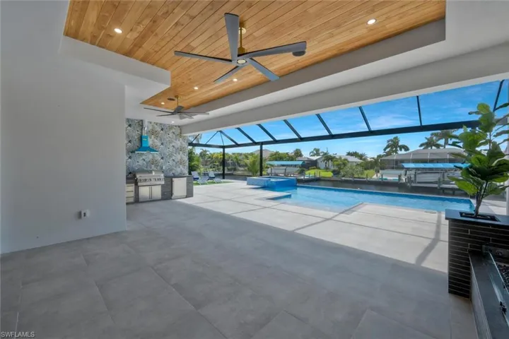 View of swimming pool with glass enclosure, a patio, a sunroom, a pool with connected hot tub, and an outdoor kitchen