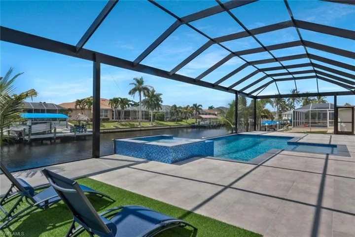 View of swimming pool featuring a water view, a pool with connected hot tub, a sunroom, a lanai, and a patio