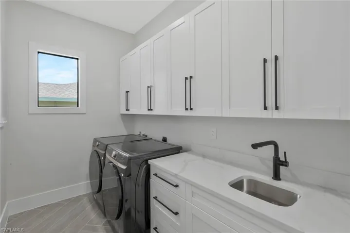 Laundry area with washing machine and dryer, cabinet space, and wood finish floors
