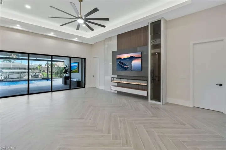 Unfurnished living room with a tray ceiling, a high ceiling, ceiling fan, and recessed lighting