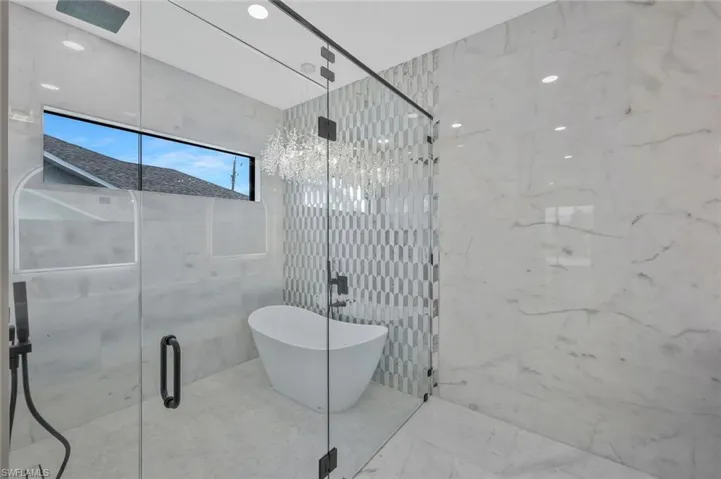 Full bathroom featuring a marble finish shower, tile walls, a freestanding tub, marble finish floors, and stone wall