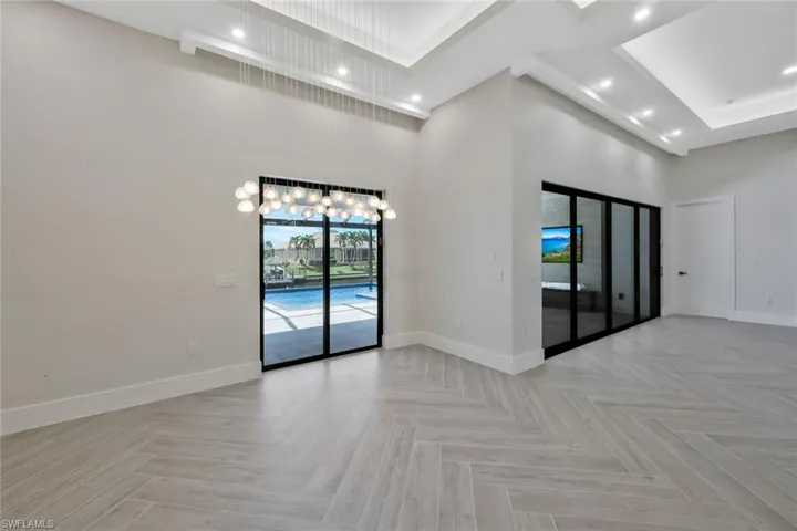 Empty room featuring a high ceiling, a chandelier, and recessed lighting