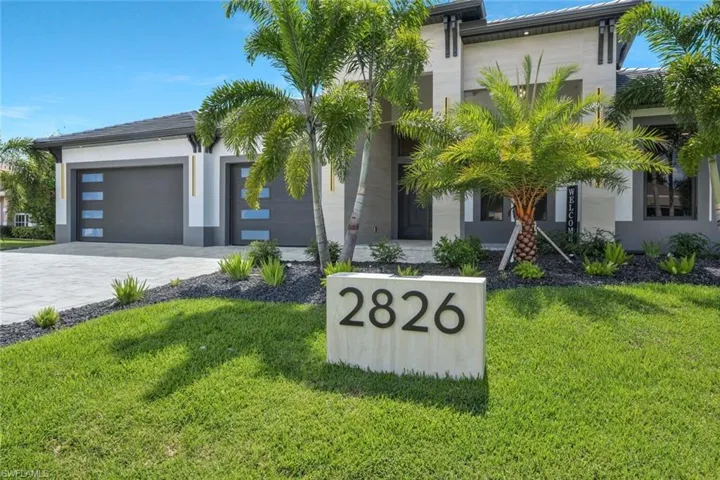 View of front of home with a front yard, decorative driveway, stucco siding, and a garage