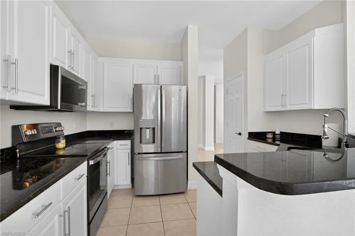 updated kitchen featuring appliances with stainless steel finishes, dark stone counters