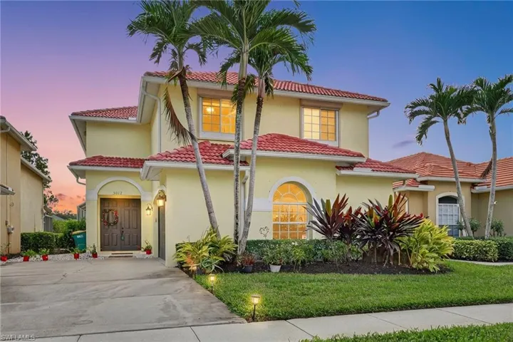 Mediterranean-style house with stucco siding, a lawn, and a tile roof