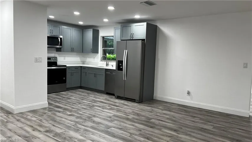 Kitchen with a sink, wood finished floors, appliances with stainless steel finishes, visible vents, and recessed lighting