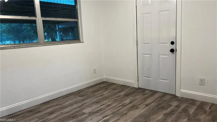 Unfurnished room with dark wood-style floors and baseboards