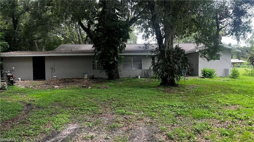 Back of house with a lawn and stucco siding