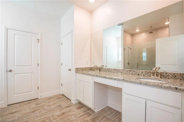 Bathroom with double vanity, a stall shower, and wood tiled floors