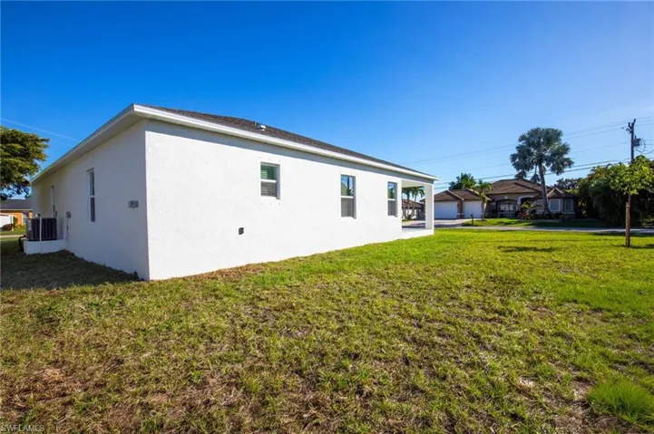 Rear view of property featuring a yard and stucco siding