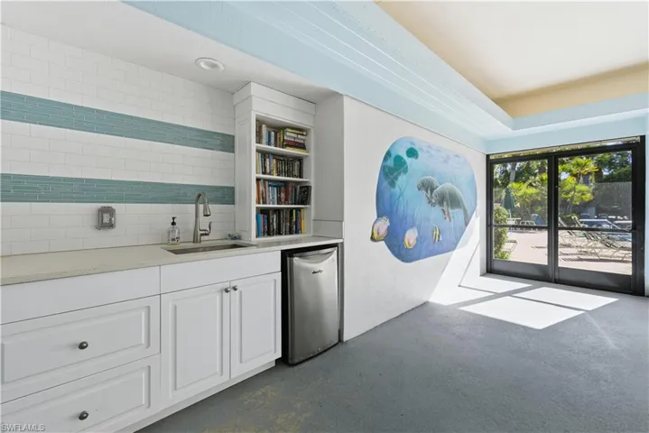 Indoor wet bar featuring white cabinets, concrete floors, open shelves, light stone countertops, and decorative backsplash