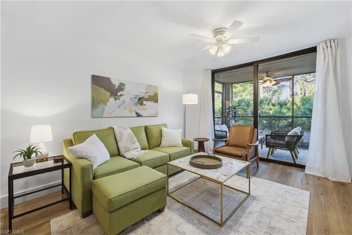 Living room featuring floor to ceiling windows, wood finished floors, and ceiling fan
