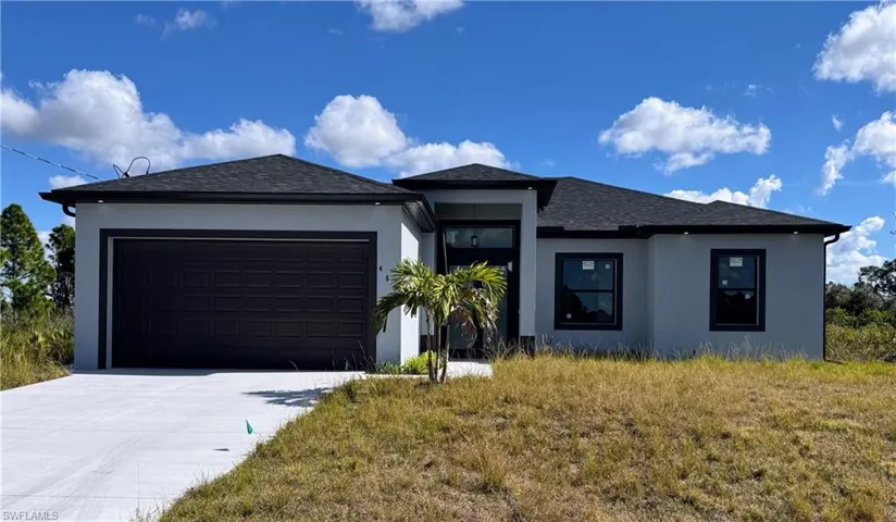 Prairie-style home with a garage, stucco siding, concrete driveway, and a shingled roof