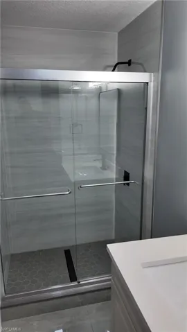 Bathroom featuring vanity, a stall shower, and a textured ceiling