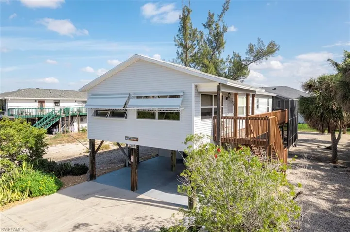 View of front of house featuring a carport, a deck, stairs, and driveway
