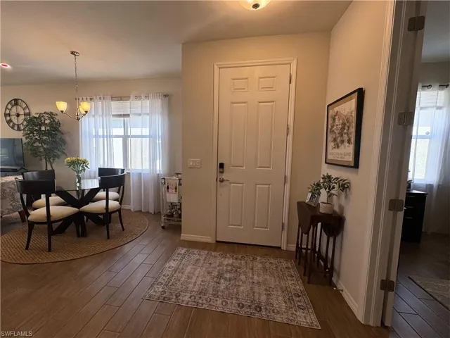 Entryway with dark wood finished floors and a chandelier