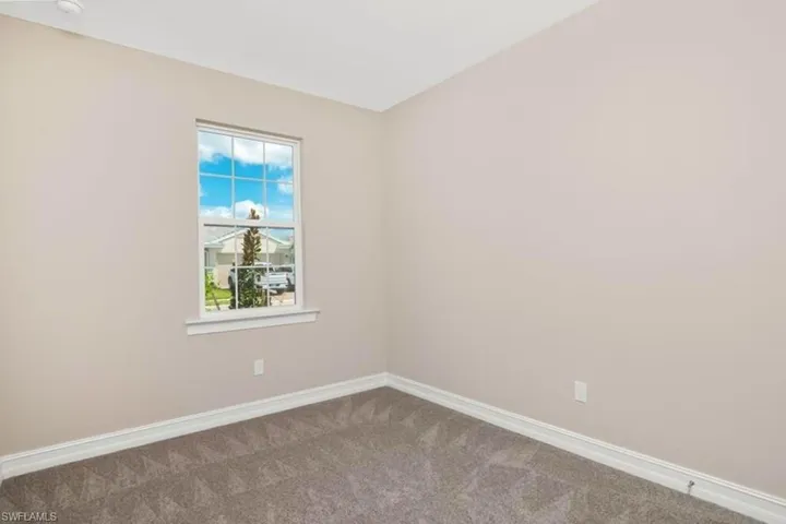 Carpeted spare room featuring baseboards