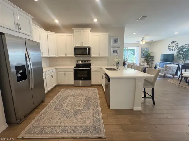 Kitchen with stainless steel appliances, white cabinetry, a peninsula, open floor plan, and recessed lighting