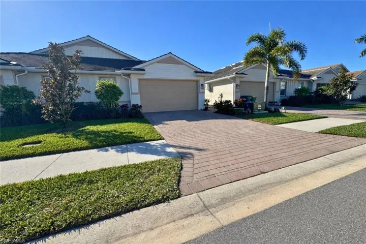 Ranch-style house with decorative driveway, a garage, and a front lawn