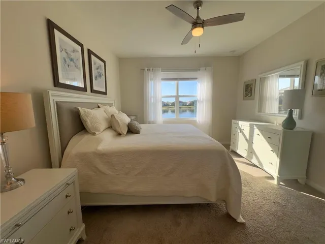 Bedroom with a water view, carpet flooring, and ceiling fan