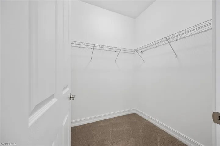 Walk in closet featuring dark carpet