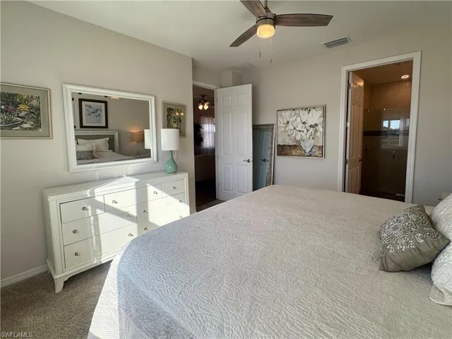 Bedroom with a ceiling fan, dark colored carpet, and ensuite bathroom