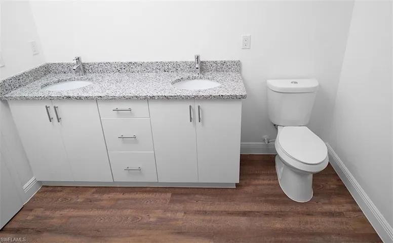 Bathroom featuring double vanity and dark wood-style flooring