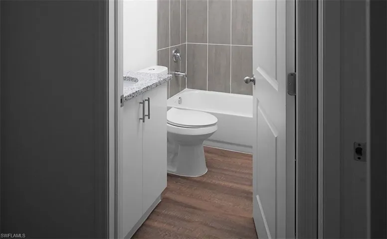 Bathroom with vanity, shower / tub combination, and dark wood-style flooring