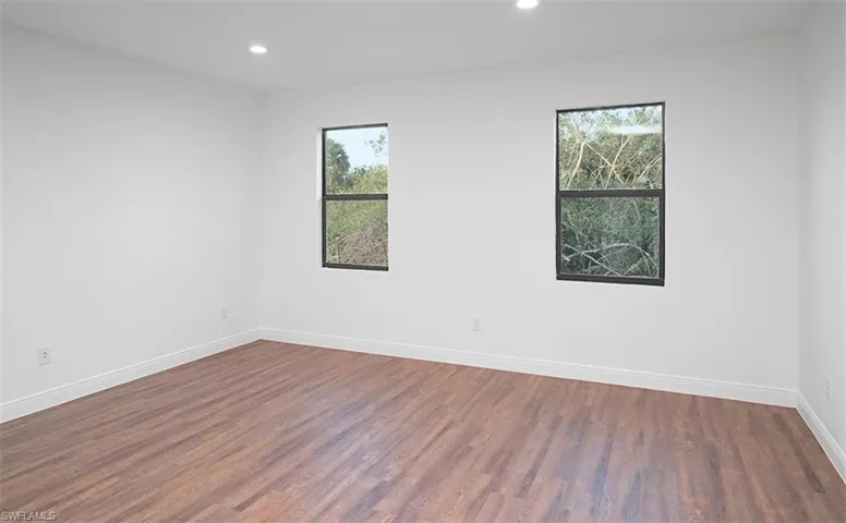 Unfurnished room featuring healthy amount of natural light, dark wood-style floors, and recessed lighting