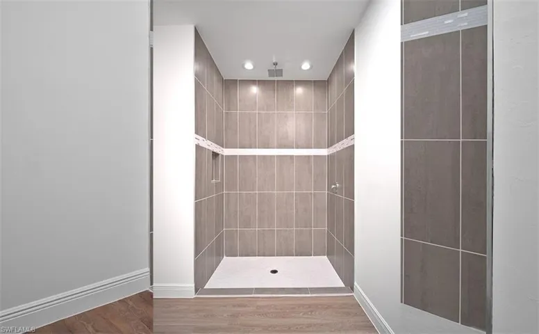 Full bath featuring wood finished floors, a tile shower, and recessed lighting