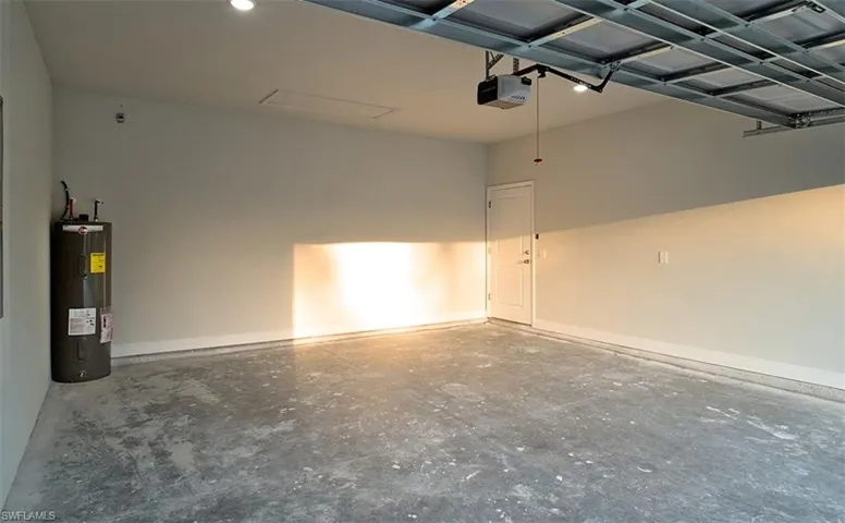 Garage featuring electric water heater and a garage door opener