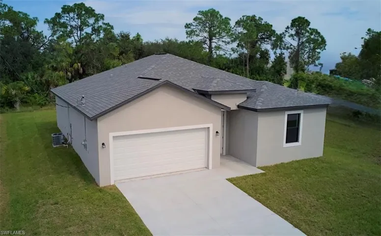Ranch-style house featuring a front lawn, a shingled roof, an attached garage, concrete driveway, and stucco siding