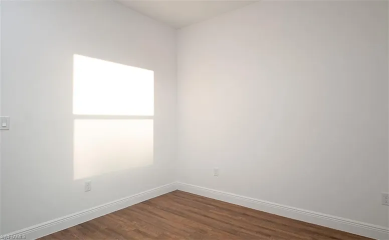 Unfurnished room featuring dark wood finished floors and baseboards