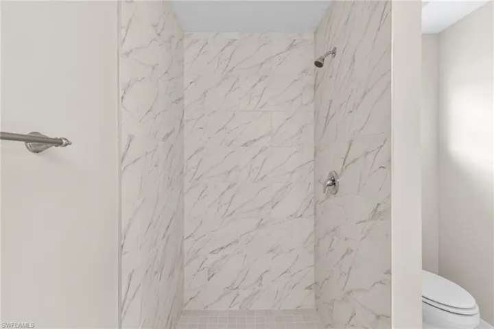Full bath featuring a marble finish shower and toilet