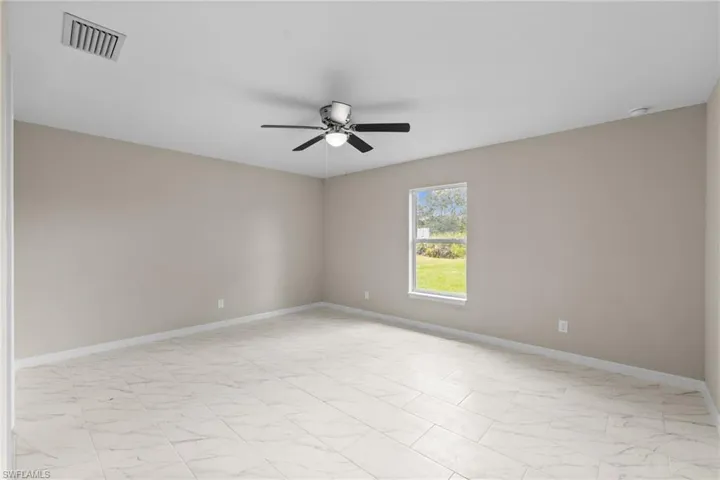 Empty room featuring ceiling fan and light marble finish floors