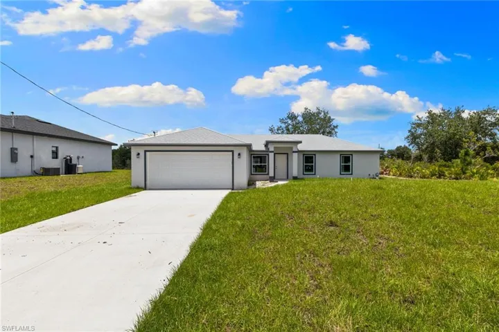 View of front facade featuring concrete driveway, a garage, a front yard, and stucco siding