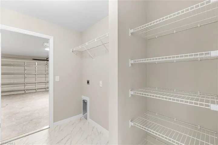 Washroom with hookup for an electric dryer, a garage, and light marble finish flooring