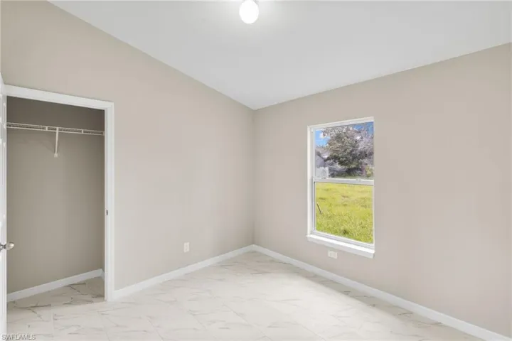 Unfurnished bedroom with light marble finish flooring, a closet, and lofted ceiling