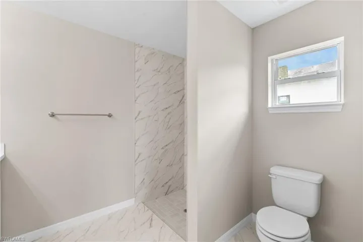 Full bathroom featuring a shower stall, vanity, and light marble finish floors
