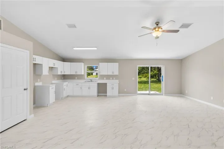 Kitchen with light countertops, lofted ceiling, white cabinetry, a ceiling fan, and open floor plan