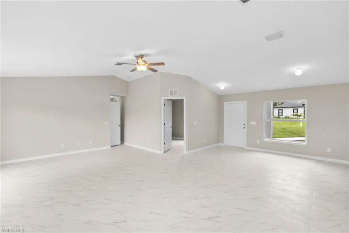 Spare room with lofted ceiling, light marble finish floors, and a ceiling fan