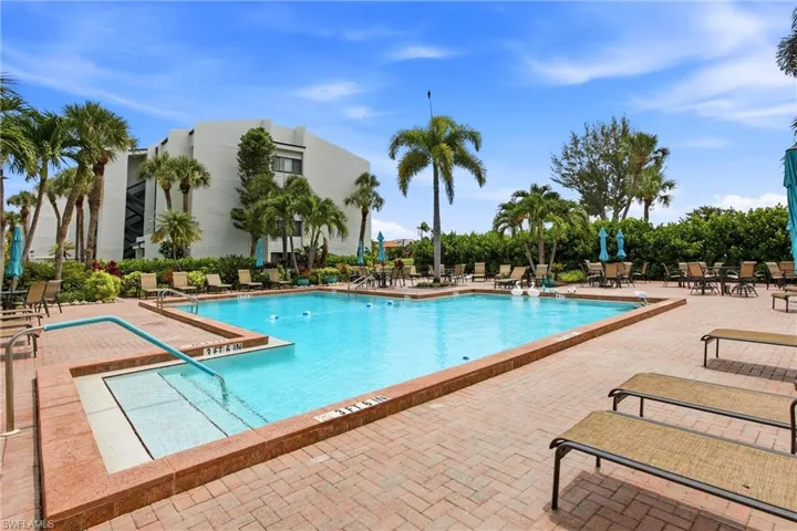 Spacious outdoor pool area featuring a rectangular pool with integrated steps, surrounded by a brick paver deck