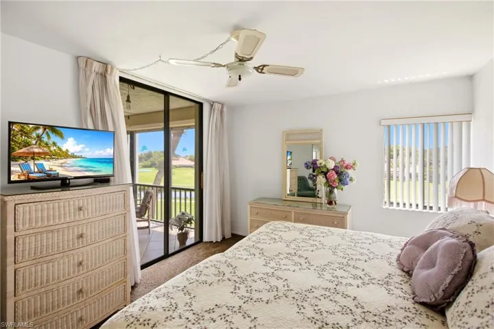Interior room featuring a sliding glass door to an outdoor balcony, overhead ceiling fan with lighting, white walls, and wood-finish flooring