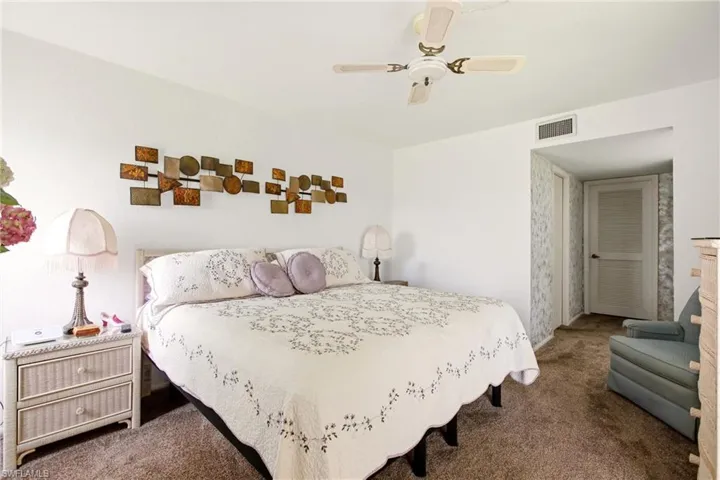 Spacious room featuring neutral carpeting, white walls, a ceiling fan, and a louvered door