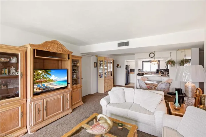 Open-concept living space featuring neutral carpeting and a smooth ceiling