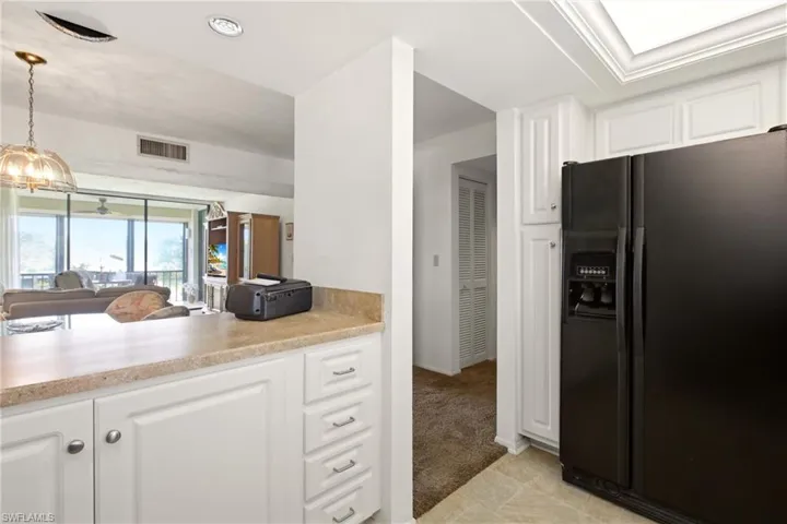 Kitchen pass-through featuring light-toned countertops and white cabinetry