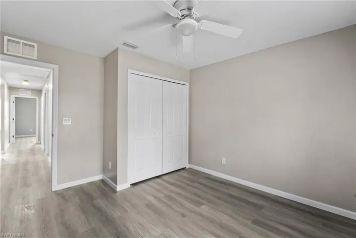 Unfurnished bedroom featuring hardwood / wood-style flooring, ceiling fan, and a closet