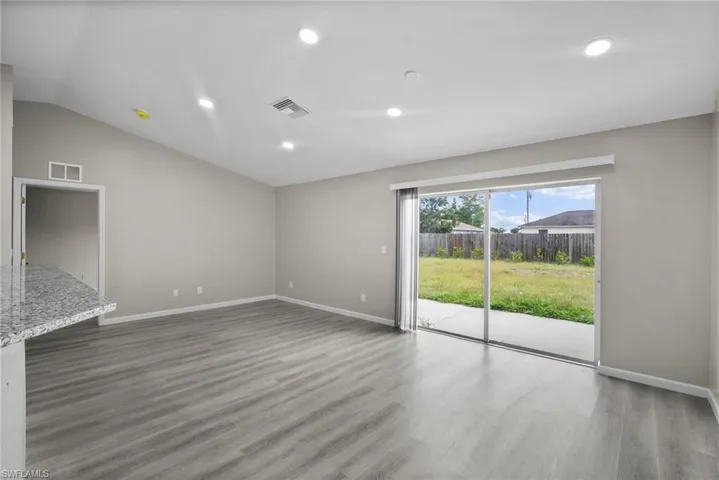 Unfurnished living room featuring wood-type flooring and lofted ceiling